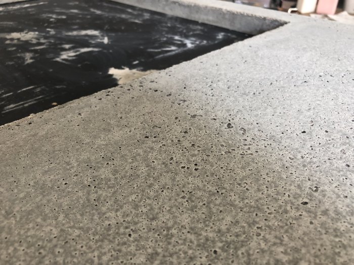 Närbild på betongyta med många hål och vitflammiga mönster, inga synliga armeringsspår.