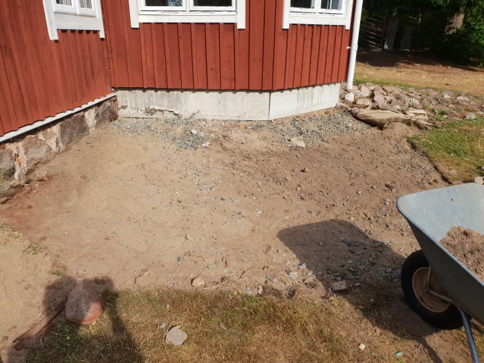 Uppgrävd mark på 7.8 m2 för betongplatta vid husgrund med synliga stöd och gammal platta.