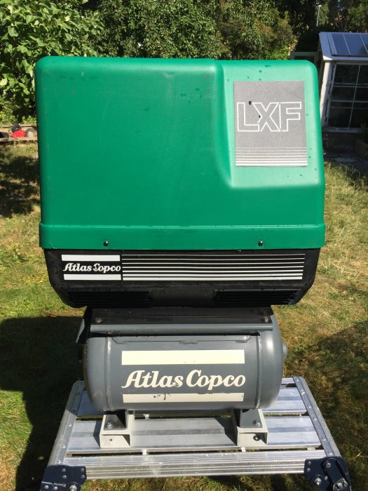 Atlas Copco oljefri kompressor på gräs, tystgående med grön kåpa och silveretikett.