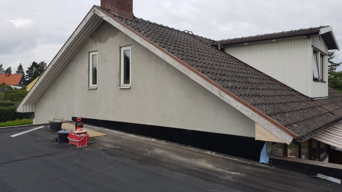 Husfasad med nyligen putsade smygarna och detaljer, arbetsmaterial synligt på taket.