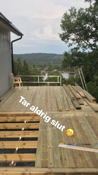Delvis byggt trätrall med sorterade brädor på ett däck under konstruktion med utsikt över naturen och en sjö.