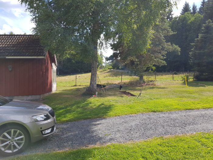 Nygrusad bilparkering på 40 kvadratmeter bredvid rött hus och grönt gräslandskap.