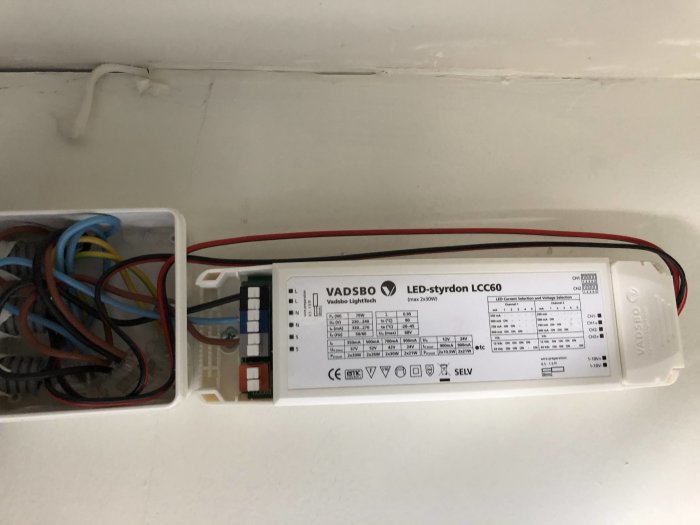 Styrdon för LED-belysning fastmonterat på vägg med anslutna färgade kablar i ett garage.
