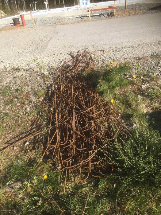 Armeringsjärn och bockade byglar på gräsmark vid byggarbetsplats.