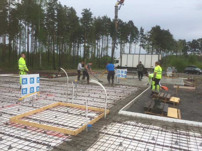 Gjutning av betongplatta med arbetare som förbereder och arbetar på byggplats.