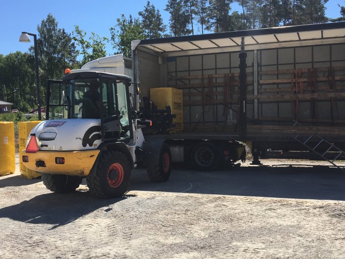 Gaffeltruck vid lastning av gula lättbetongblock från Xella Ytong på lastbilsflak under en solig dag.