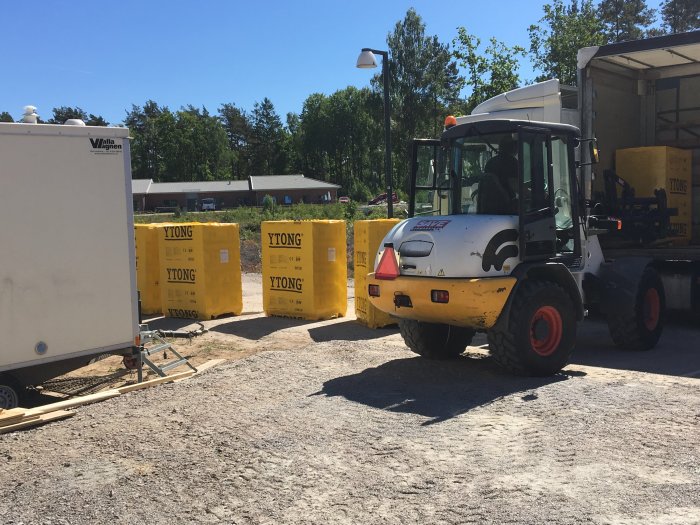 Byggarbetsplats med Ytong lättbetongblock och gaffeltruck, skyddade ytor synliga.