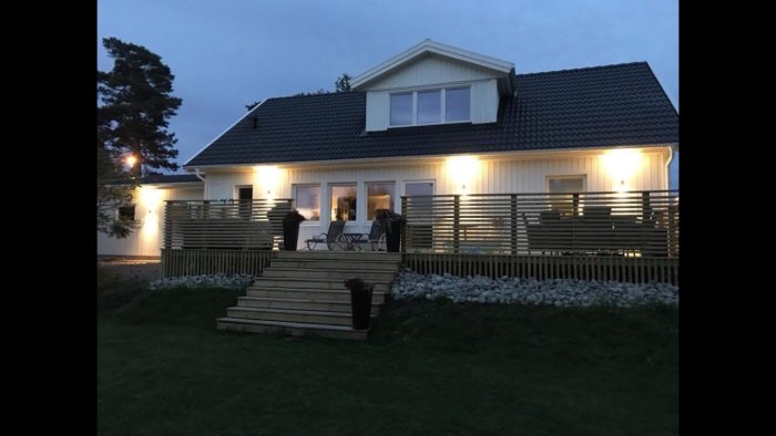 Ett nyligen renoverat Älvsbyhus på kvällen med tända utelampor, stenläggning och en välansad trädgård.