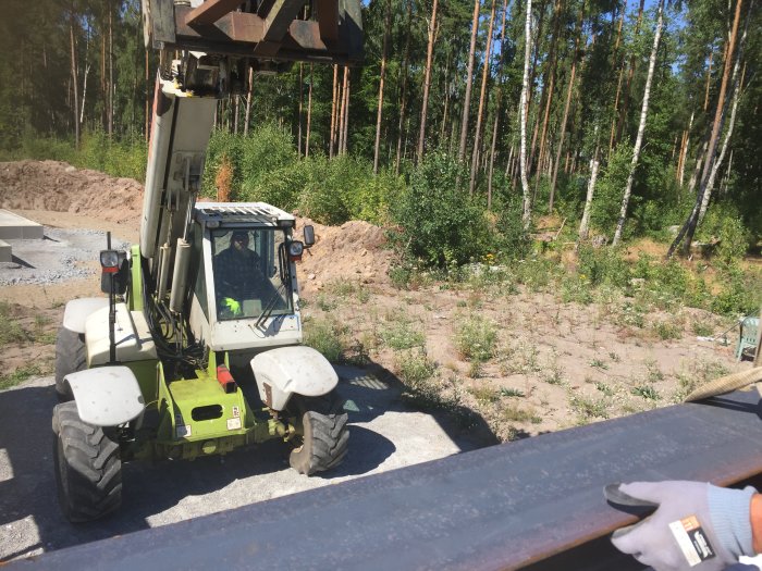 Lyft av en stor HEAB 180 järnbalk med en teleskoplastare på en byggarbetsplats.