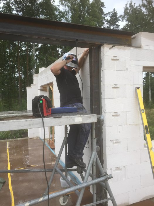 Person som arbetar med att installera en stor järnbalk för en utbyggnad.