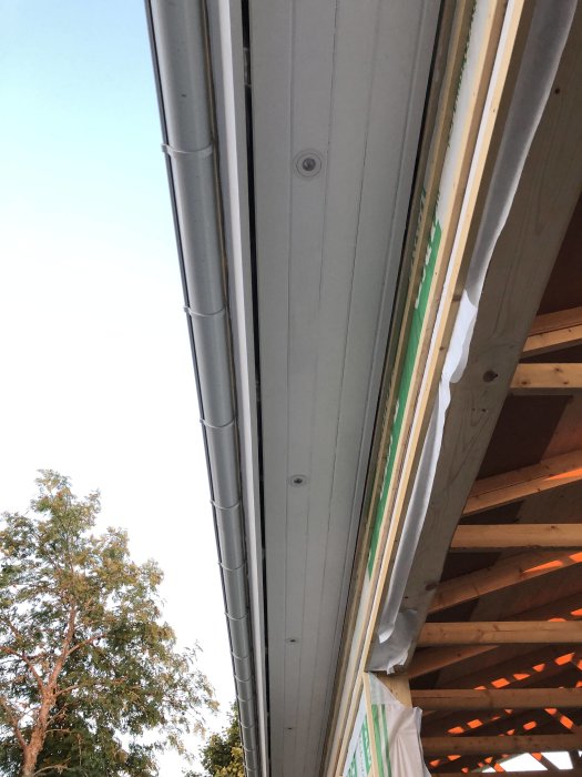 Vy underifrån av en nyligen installerad låda med spotlights bredvid en yttervägg och takkonstruktion.