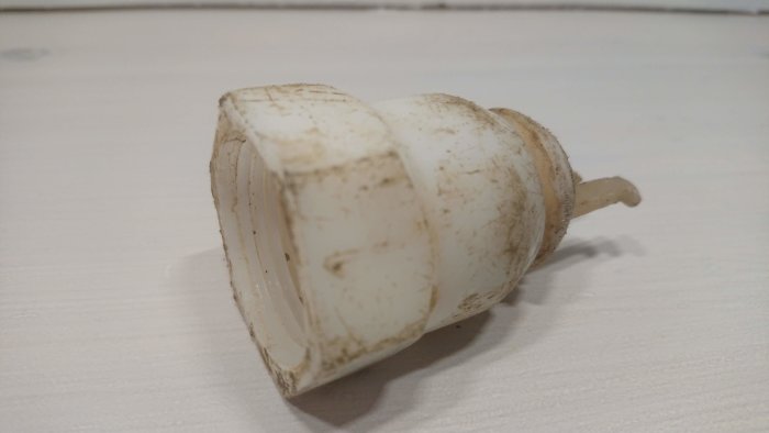 Trasig vit ventil från en gårdspump med 32-33 mm gängning.