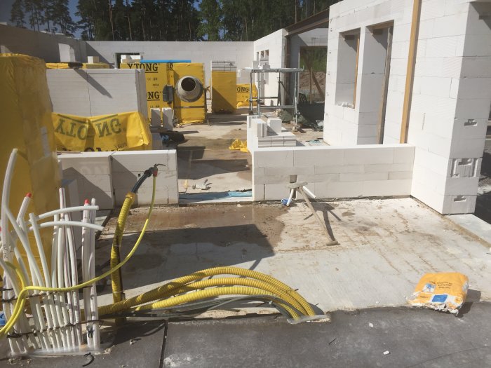 Byggarbetsplats med uppförande av bärande innervägg av betongblock mellan garage och hus.