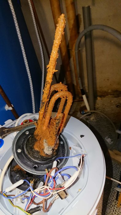 Korroderad offeranod och interna komponenter i en varmvattenberedare, tydliga tecken på kalkavlagringar och rost.