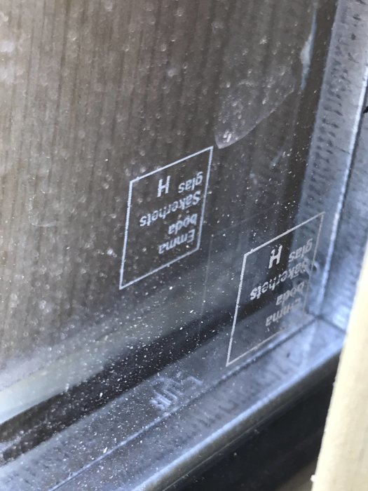 Närbild på ett fönster med säkerhetsmärkning som indikerar laminering.