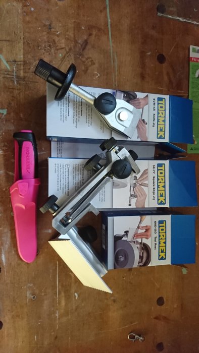 Tormek T4 slipverktyg och en rosa Morakniv på en träyta med förpackningar.