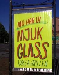 Reklamskylt med texten 'NU HAR VI MJUK GLASS VALLA GRILLEN' i gula och röda bokstäver mot grön bakgrund.