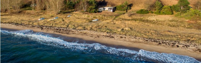 Luftvy över ett hus vid strandkanten i Löderups strandbad.