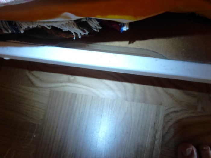 Ventilationshål med försänkning i garderob från 50-talet upplyst av ficklampa, trägolv synligt.