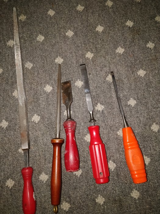 Fem olika verktyg på matta, inklusive ett orange Woodpecker-skrapverktyg.
