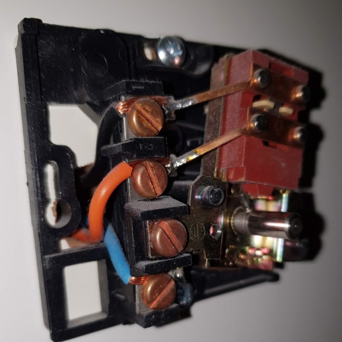 Äldre modell av termostat för golvvärme med kopparledningar och skruvanslutningar.