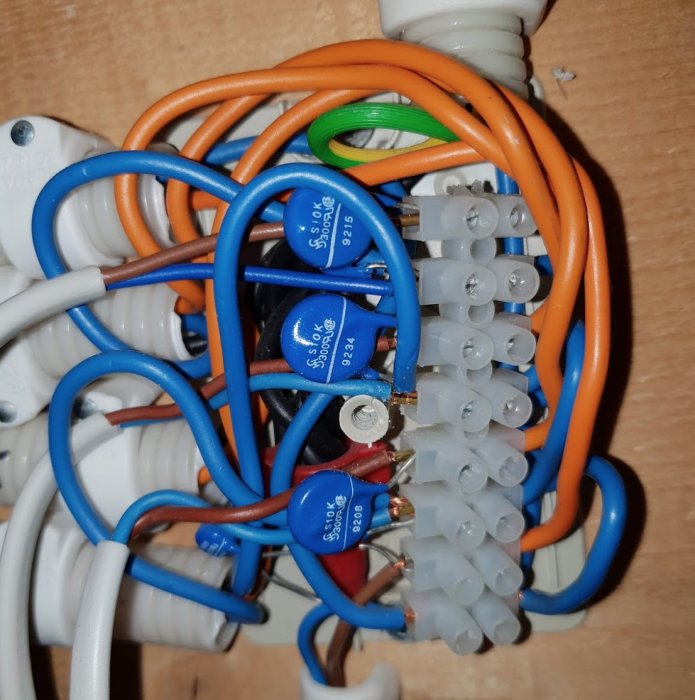 En öppnad termostat med exponerade elektriska komponenter såsom anslutna kablar och kondensatorer inomhus.