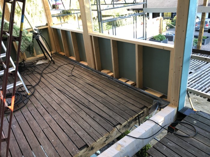 Pågående byggprojekt med nyinstallerade utegipsskivor på en uteplats i soligt väder, inklusive verktyg och byggmaterial.