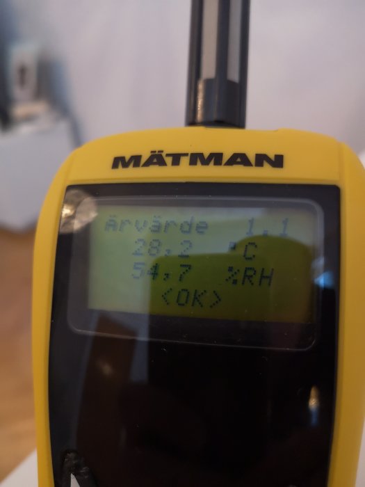 Digital termometer som visar en inomhustemperatur på 28,7 grader Celsius och 54,7 % luftfuktighet.