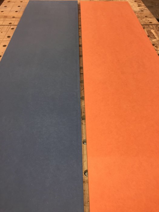 Blå och orange valchromat plattor på ett arbetsbord inför snickeriprojekt.
