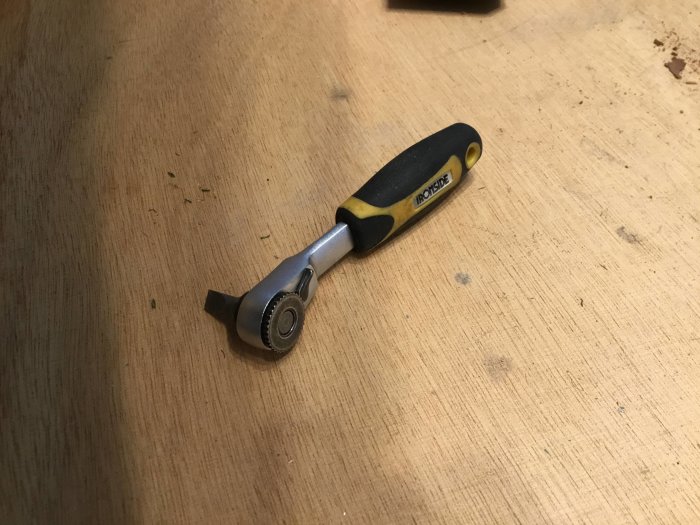 Spärrskaft med gult och svart handtag på träbakgrund.