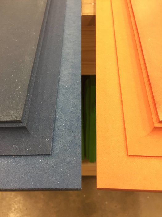Delvis limmad dörrpanel i byggprocess, synliga limskikt mellan lager av blå och orange skivmaterial.