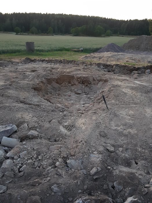 Uppgrävd mark med stenar och en grop där en grunden till en byggnad har tagits bort.