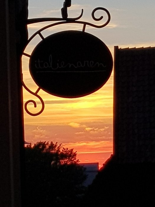 Skylt med texten "italienaren" mot en solnedgång i Visby.