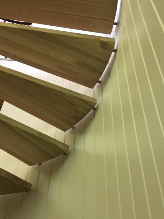 Närbild av en modern, halvfärdig trätrappa med vita väggar.