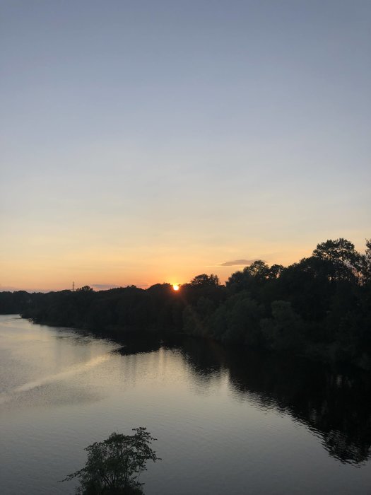 Solnedgång över en flod utan moln på himlen.