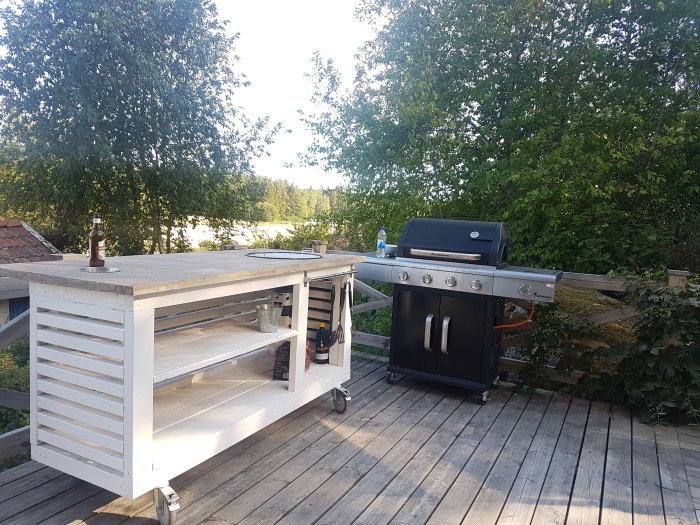 Nybyggd grillbänk av trä med hårdvaxoljad skiva på en träterrass bredvid en gasolgrill.