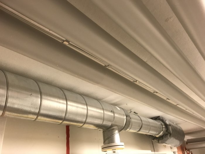 Isolerade ventilationsrör i källartak med synliga anslutningar och isolerstrumpa.