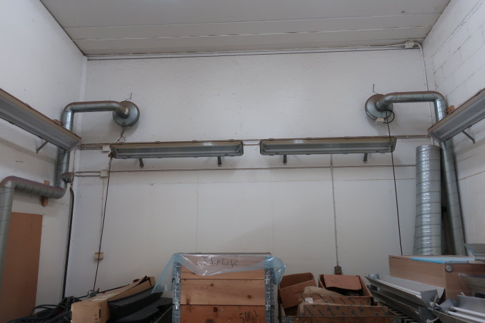 Spirorör monterade längs ett vitmålat garage-tak bland rör och förvaringslådor.