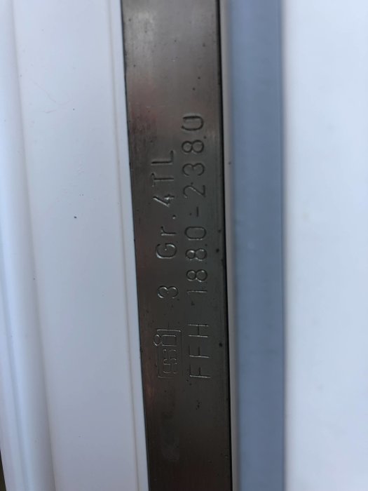 Närbild på undersidan av en balkongdörr med synlig tillverkarstämpel och serienummer.