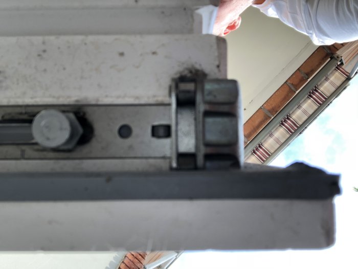 Undersida på en balkongdörr med synligt beslag och del av låsmekanism, fotograferad inifrån en lägenhet.