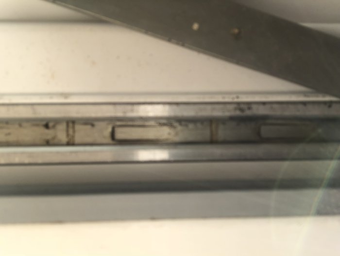 Detaljbild av undersidan av en balkongdörr visande spåret och låsmekanismen från insidan.