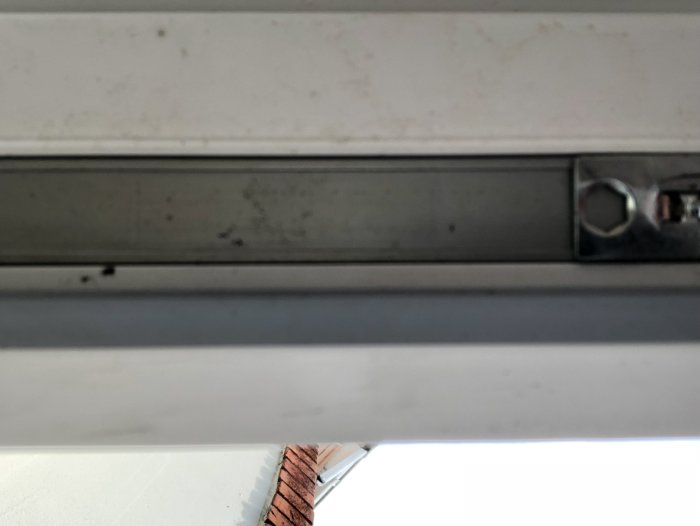 Undersidan av en balkongdörr med låsmekanism, fotograferad inifrån.