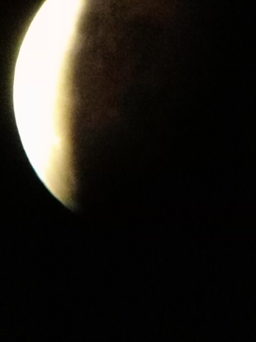 En delvis suddig bild av månen tagen genom ett teleskop med synlig terminatorlinje.