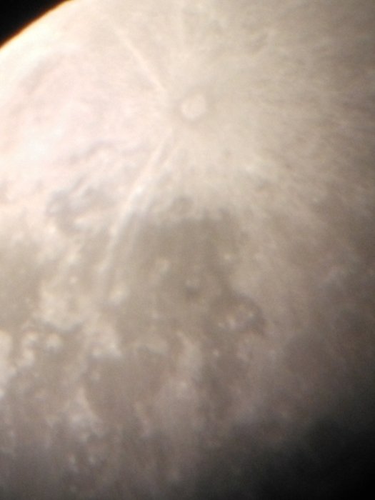 Fotografi taget genom teleskop som visar närbild av månens yta med kratrar.