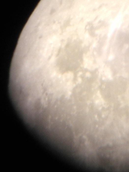 Närbild av månens yta tagen genom ett teleskop med synliga kratrar och formationer.