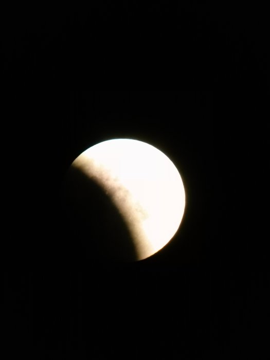 Delvis suddig bild av månen tagen genom ett teleskop mot en mörk bakgrund.