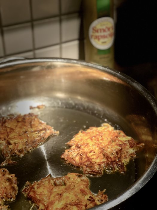 Smörstekt rösti i stekpanna med oljeflaska i bakgrunden.