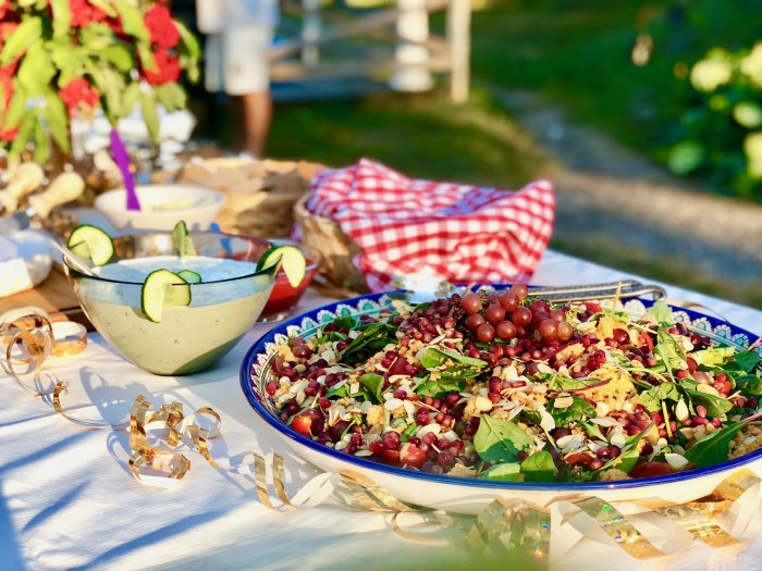 Färgrik couscoussallad med granatäpple, vindruvor och rostade mandlar på ett festligt dukat bord.