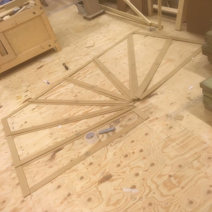 Mall av träspikar utformad som en svängd trappa på ett snickerigolv, använd för att planera trappbygget.