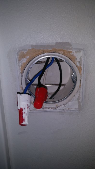 Elektriska kablar med blå och svart tråd kopplade med skarvhylsor i en väggdosa.